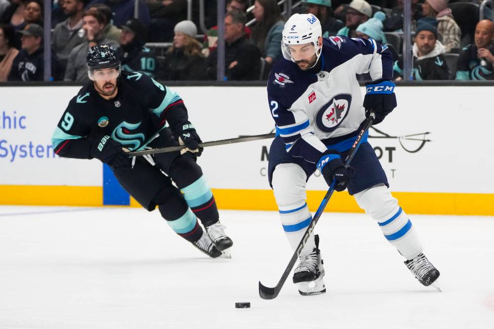Lindsey Wasson / The Associated Press
Winnipeg Jets defenceman Dylan DeMelo looks to move the puck as Seattle Kraken centre Chandler Stephenson looks on during the second period.