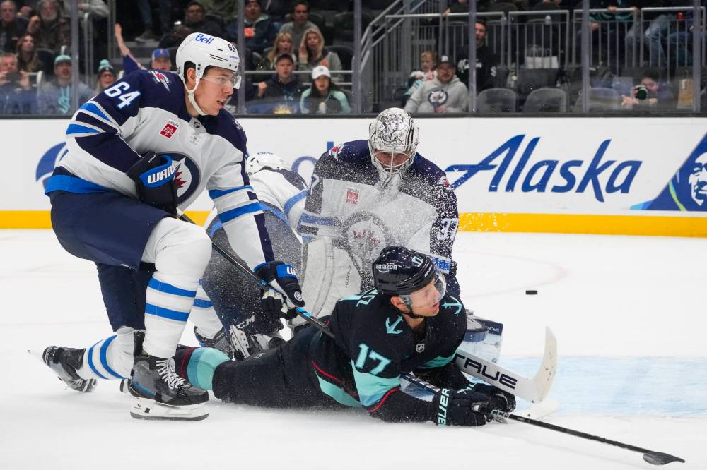 Lindsey Wasson / The Associated Press
Winnipeg Jets defenceman Logan Stanley and goaltender Connor Hellebuyck keep the puck and Seattle Kraken centreman Jaden Schwartz out of the goal during the second period Thursday in Seattle.