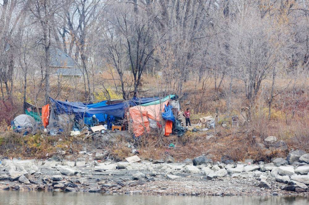 MIKE DEAL / FREE PRESS
A person stands outside an encampment at the foot of the CNR Main Line Bridge Tuesday morning.