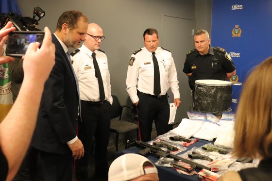Justice Minister Matt Wiebe, WPS Insp. Elton Hall, WPS deputy chief Gene Bowers and WPS Const. Jason Michalyshen assess the guns, drugs and luxury items seized. (Tyler Searle / Winnipeg Free Press)
