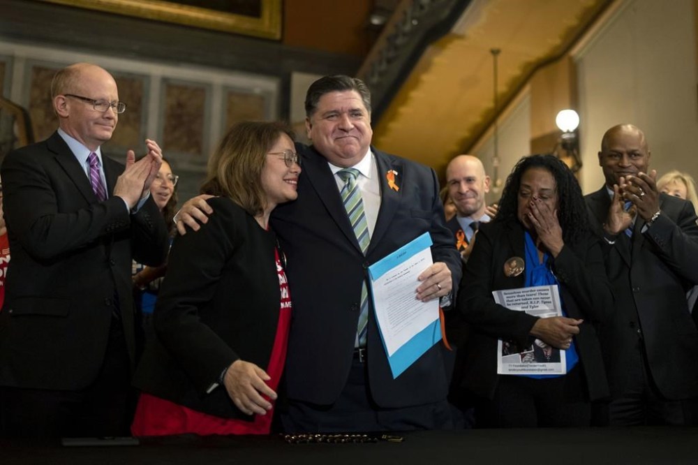 FILE - Illinois Gov. J.B. Pritzker hugs gun control advocate Maria Pike after he signed comprehensive legislation to ban military-style firearms on Jan. 10, 2023, at the Illinois State Capitol in Springfield, Ill. (Brian Cassella/Chicago Tribune via AP, File)