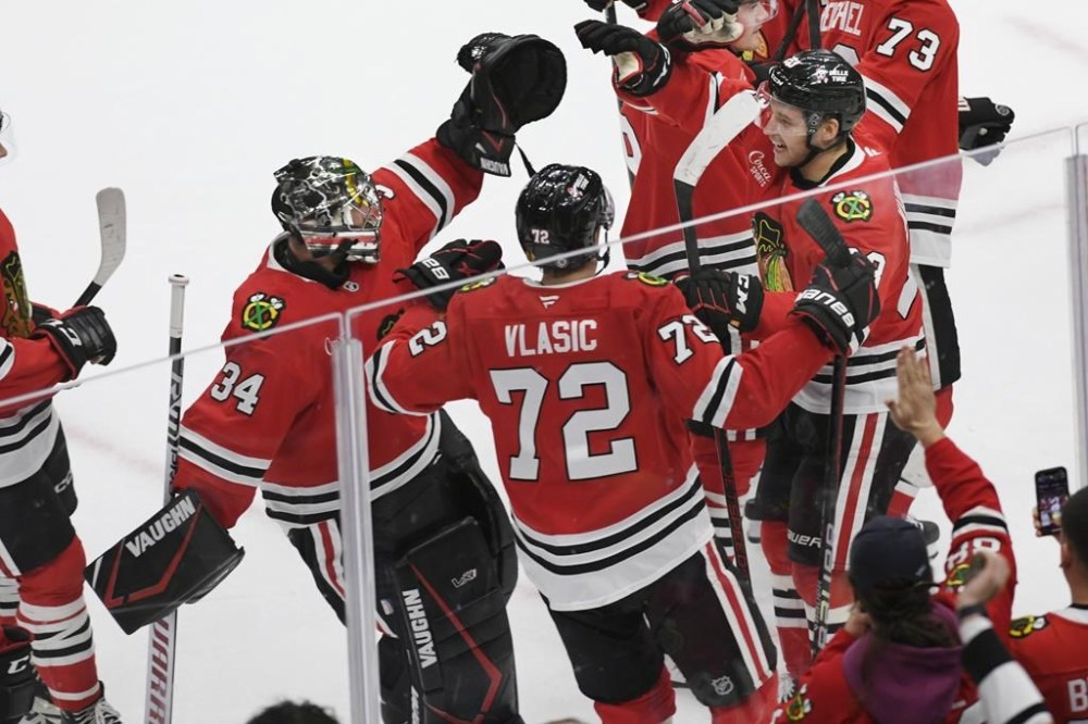 Chicago Blackhawks' Philipp Kurashev (23), celebrates with goalie Petr Mrazek (34), and teammate Alex Vlasic (72), after scoring the winning goal to defeat the Minnesota Wild 2-1 in overtime of an NHL hockey game Sunday, Nov. 10, 2024, in Chicago. (AP Photo/Paul Beaty)