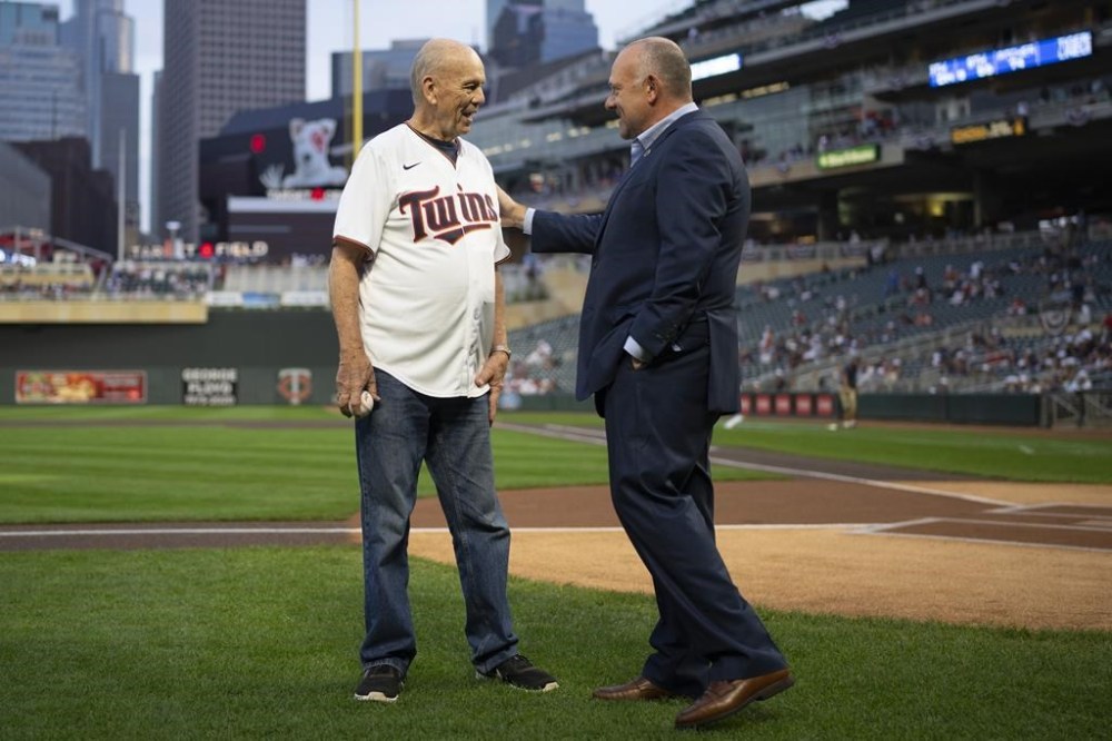 FILE - Associated Press staff photographer Jim Mone, left, is congratulated by Minnesota Twins President and CEO Dave St. Peter after he threw out the ceremonial first pitch before the Minnesota Twins play the Detroit Tigers in a baseball game, Sept. 30, 2021 in Minneapolis. (Jeff Wheeler/Star Tribune via AP, File)