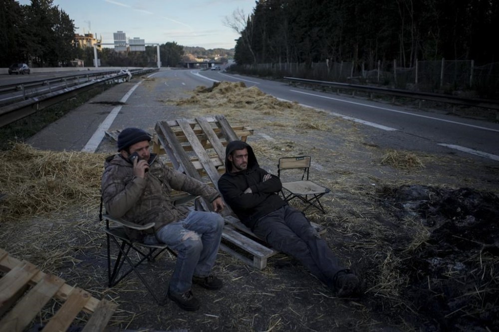 FILE- Farmers sit on a highway after spending the night at a barricade in Aix-en-Provence, southern France, Tuesday, Jan. 30, 2024. (AP Photo/Daniel Cole, File)