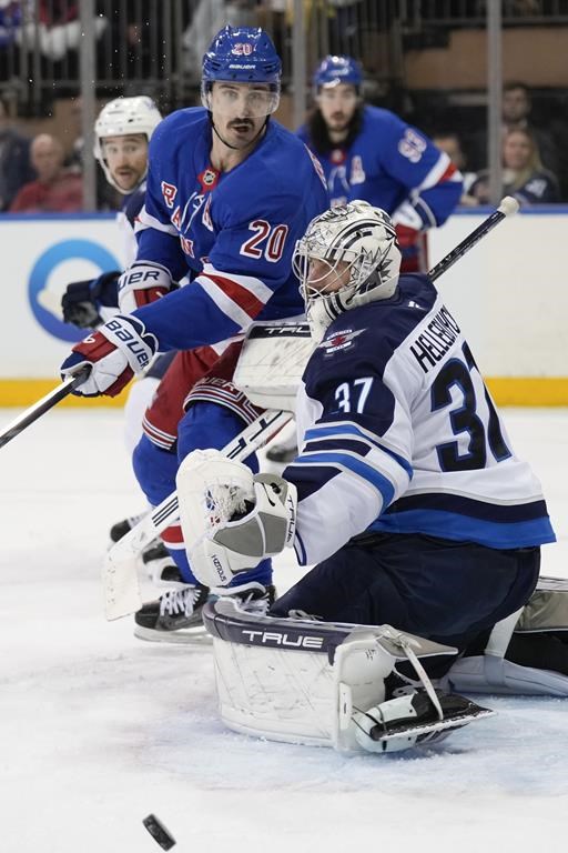 New York Rangers' Chris Kreider, top, and Winnipeg Jets goaltender Connor Hellebuyck watch as the puck passes nearby during the third period of an NHL hockey game Tuesday, Nov. 12, 2024, in New York. The Jets defeated the Rangers 6-3. (AP Photo/Seth Wenig)
