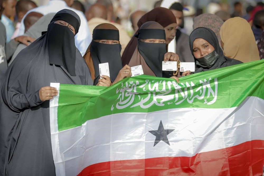 People display the Somaliland flag as they wait to cast their vote during the 2024 Somaliland presidential election at a polling station in Hargeisa, Somaliland, Wednesday, Nov. 13,2024. (AP Photo/Abdirahman Aleeli)