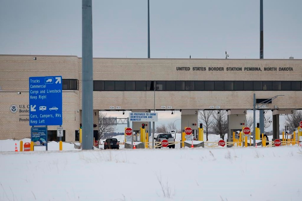 A lone car enters the US as people block highway 75 with heavy trucks and farm equipment and access to the Canada/US border crossing at Emerson, Man., Thursday, Feb. 10, 2022. Two men are to stand trial on human smuggling charges this week, almost three years after a family from India was found frozen to death on the border between Manitoba and Minnesota. THE CANADIAN PRESS/John Woods