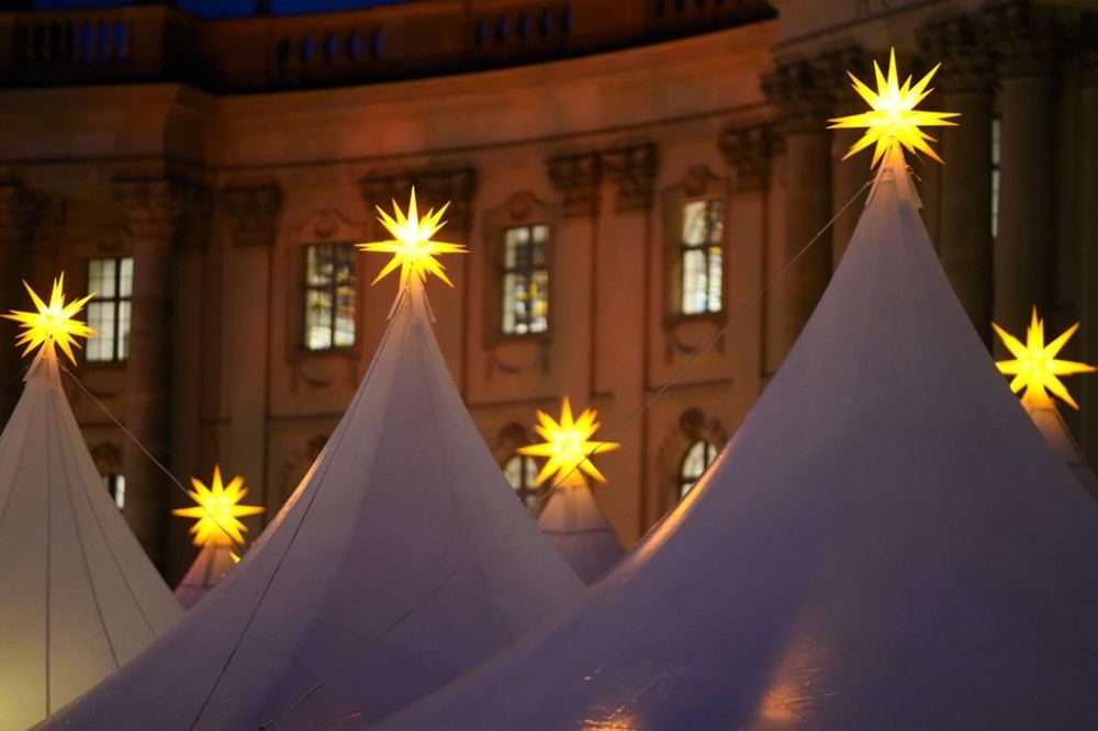 Christmas stars illuminate the top of the tents of the Christmas market at Bebelplatz in the city center of Berlin, Germany, Monday, Nov. 25, 2024. (AP Photo/Markus Schreiber)