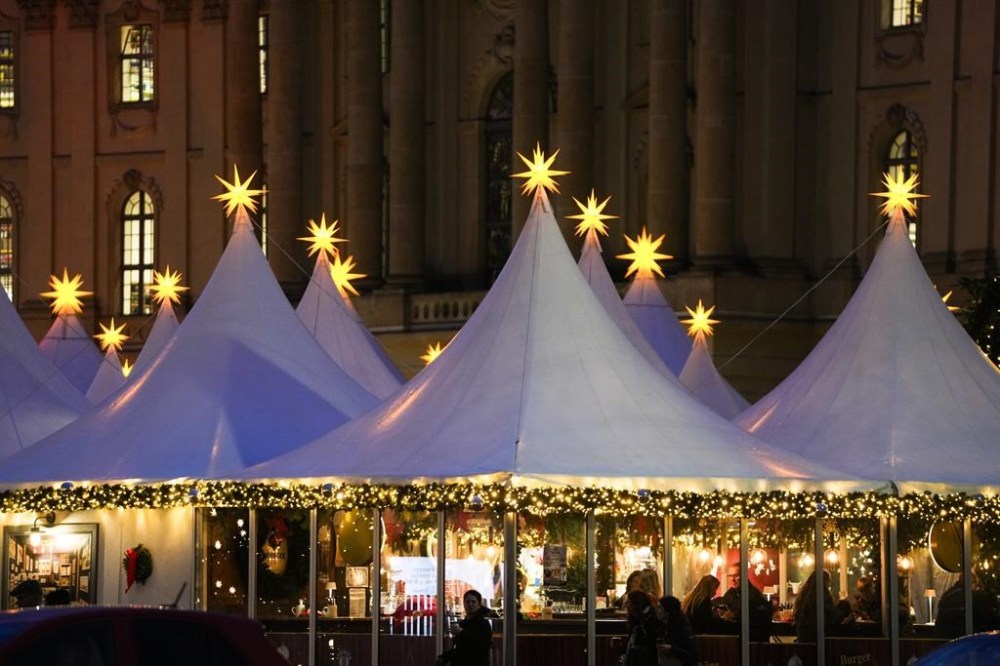 Christmas stars illuminate the top of the tents of the Christmas market at Bebelplatz in the city center of Berlin, Germany, Monday, Nov. 25, 2024. (AP Photo/Markus Schreiber)