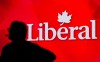 A Liberal Party of Canada logo is shown on a giant screen as a technician looks on during day one of the party's biennial convention in Montreal on Feb. 20, 2014. THE CANADIAN PRESS/Graham Hughes