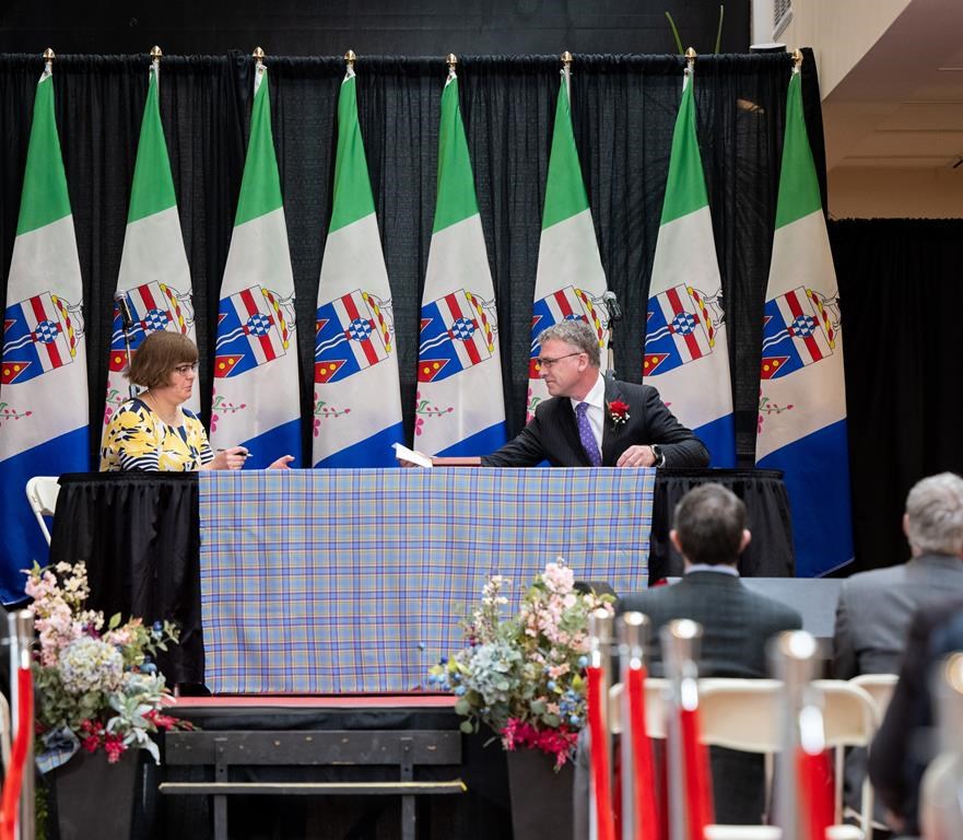 Yukon MLA Richard Mostyn passes a signed oath of office to Yukon Commissioner Angelique Bernard at the swearing in ceremony in the Yukon Government Legislature foyer, in Whitehorse, Monday, May 3, 2021. THE CANADIAN PRESS/Mark Kelly