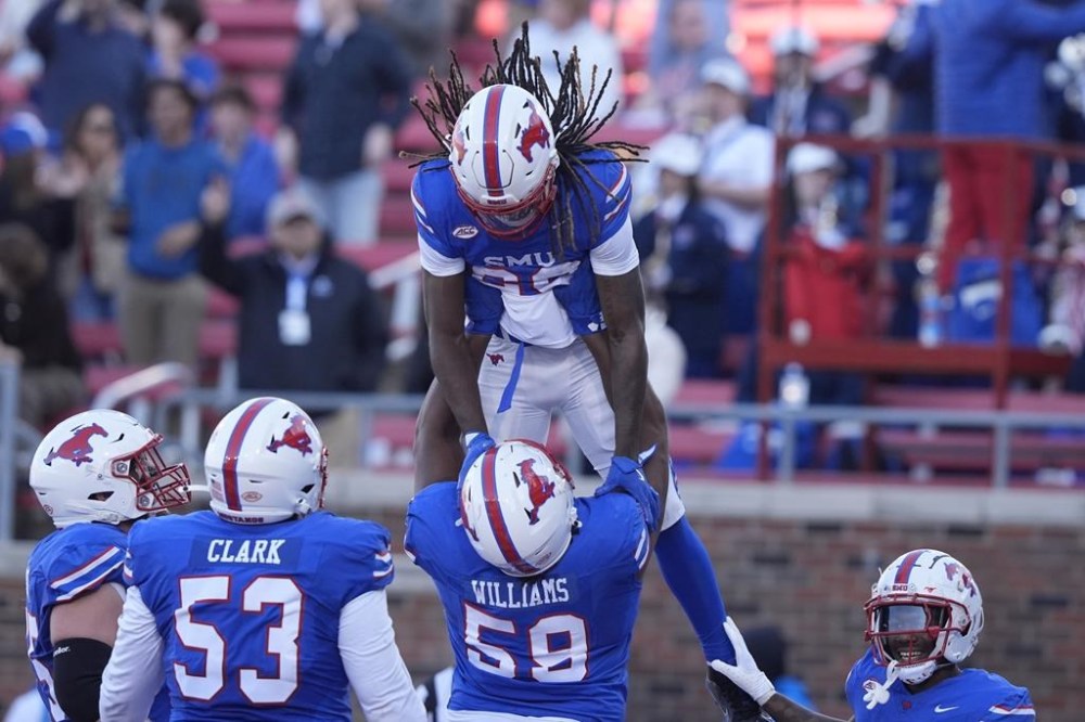 SMU wide receiver Derrick McFall (20) is lifted by teammate defensive end Isaiah Smith (58) after McFall scored a touchdown during the first half of an NCAA college football game against California, Saturday, Nov. 30, 2024, in Dallas. (AP Photo/LM Otero)