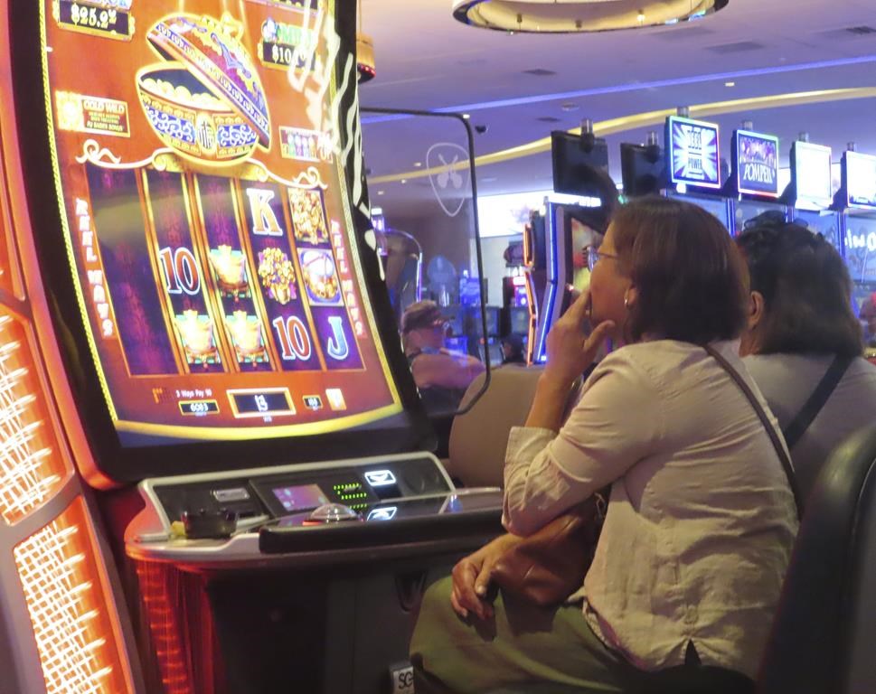 A gambler smokes while playing a slot machine at the Hard Rock casino in Atlantic City N.J. on Aug. 8, 2022. (AP Photo/Wayne Parry)