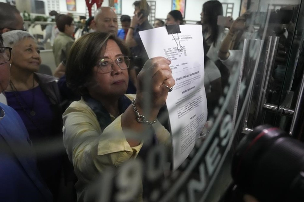 Former Senator Leila de Lima shows an impeachment complaint which they will file against Philippine Vice President Sara Duterte as they wait for the secretary general to receive it at the House of Representatives in Quezon City, Philippines on Monday, Dec. 2, 2024. (AP Photo/Aaron Favila)