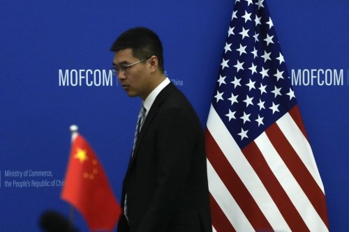 FILE - A Chinese official walks by the China and U.S. national flags before a meeting between Commerce Secretary Gina Raimondo and Chinese Minister of Commerce Wang Wentao at the Ministry of Commerce in Beijing on Aug. 28, 2023. (AP Photo/Andy Wong, Pool, File)