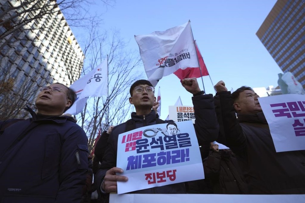 South Koreans shout slogans with signs reading