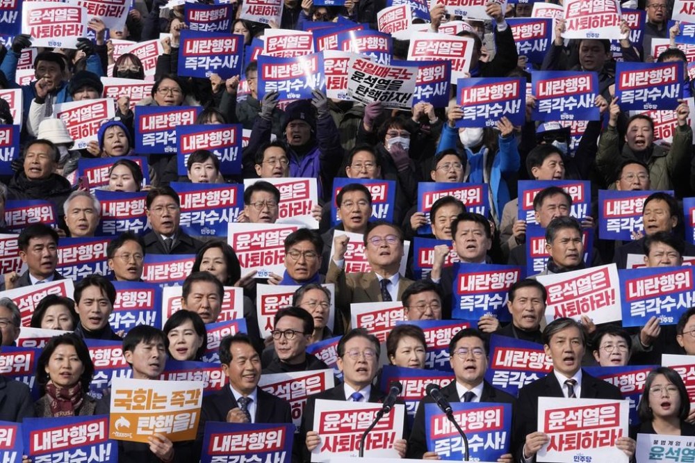 South Korea's main opposition Democratic Party leader Lee Jae-myung, bottom center, shout slogans during a rally against President Yoon Suk Yeol at the National Assembly in Seoul, South Korea, Wednesday, Dec. 4, 2024. The signs read