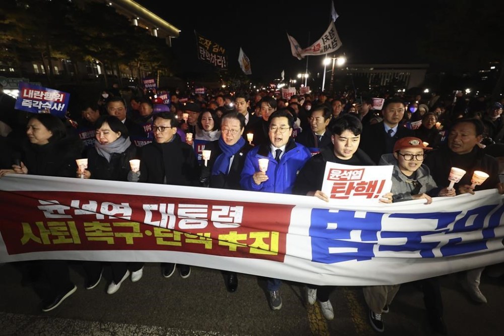 South Korea's main opposition Democratic Party leader Lee Jae-myung, center left, marches with his party members during a rally against the President Yoon Suk Yeol at the National Assembly in Seoul, South Korea, Wednesday, Dec. 4, 2024. The signs read