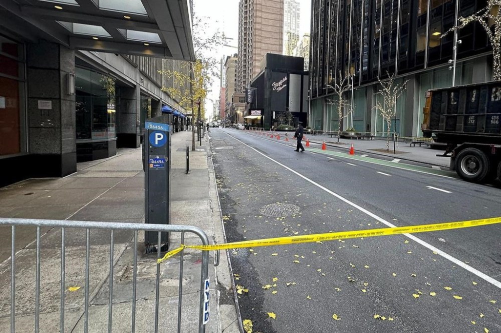 A New York police officer walks outside a hotel where a shooting occurred in midtown Manhattan, Wednesday, Dec. 4, 2024, in New York. (AP Photo/Joe Frederick)