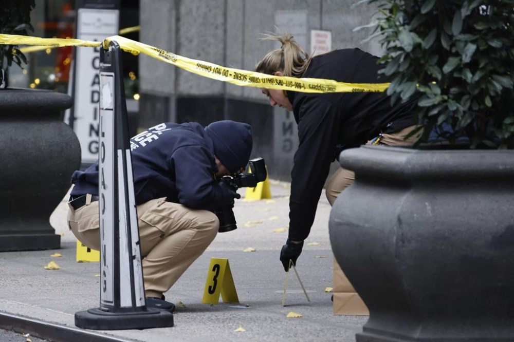 Members of the New York police crime scene unit photograph bullets lying on the sidewalk as they investigate the scene outside the Hilton Hotel in midtown Manhattan where Brian Thompson, the CEO of UnitedHealthcare, was fatally shot, Wednesday, Dec. 4, 2024, in New York. (AP Photo/Stefan Jeremiah)