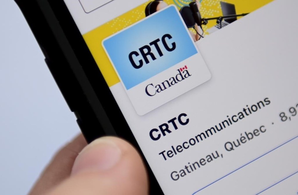 A person navigates to the online social-media pages of the CRTC on a cell phone in Ottawa on Monday, May 17, 2021. THE CANADIAN PRESS/Sean Kilpatrick