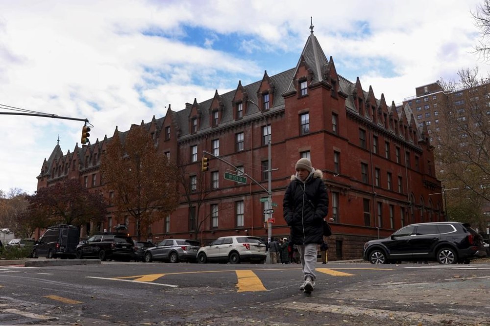 A woman crosses Amsterdam Avenue outside the HI New York City hostel, Thursday, Dec. 5, 2024, in New York, where police say the suspect in the killing of UnitedHealthcare CEO Brian Thompson may have stayed.(AP Photo/Yuki Iwamura)