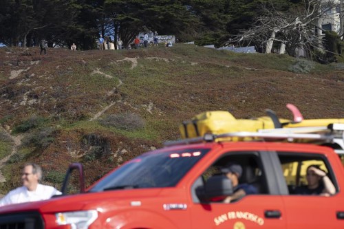 The Fire Department patrols at Ocean Beach in San Francisco while people watch the waves on higher ground during a tsunami warning on Thursday, Dec. 5, 2024. (AP Photo/Emily Steinberger)