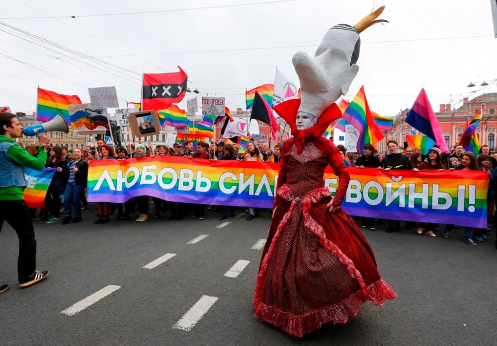 FILE - A gay rights activist wearing a mask walks ahead of gay rights activists during a May Day rally in St. Petersburg, Russia, on May 1, 2014. (AP Photo, File)