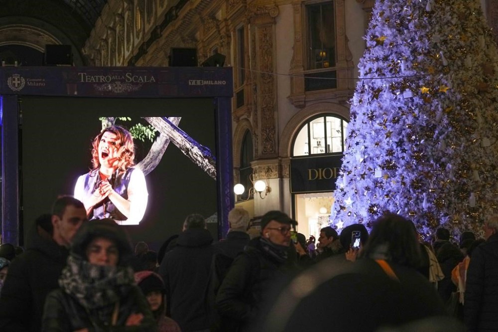 People watch a screen at the Galleria Vittorio Emanuele II during the opening of the 2024-25 season featuring Giuseppe Verdi's 'La Forza del destino' at the Milan's Opera House La Scala, Italy, Saturday, Dec. 7, 2024. (AP Photo/Luca Bruno)