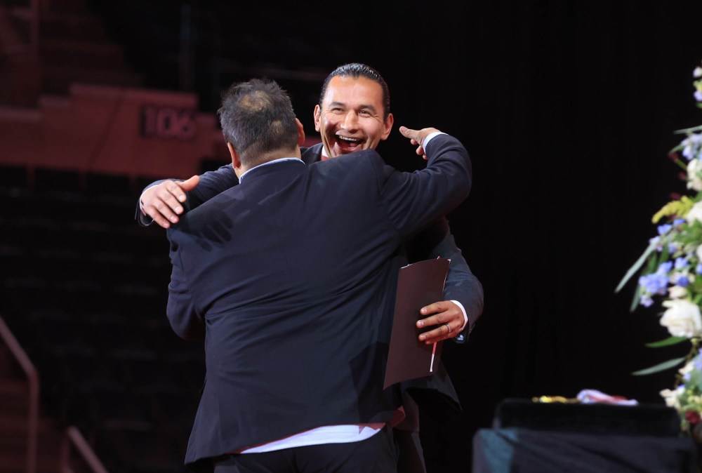 Premier Wab Kinew, gives Niigaan Sinclair a big hug as he enters the stage to speak Sunday. (Ruth Bonneville / Free Press)