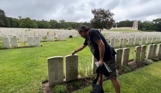 Randall McKenzie places a penny on Pte. Oswald McCorrister’s grave in France as a token of his respect. (Supplied)