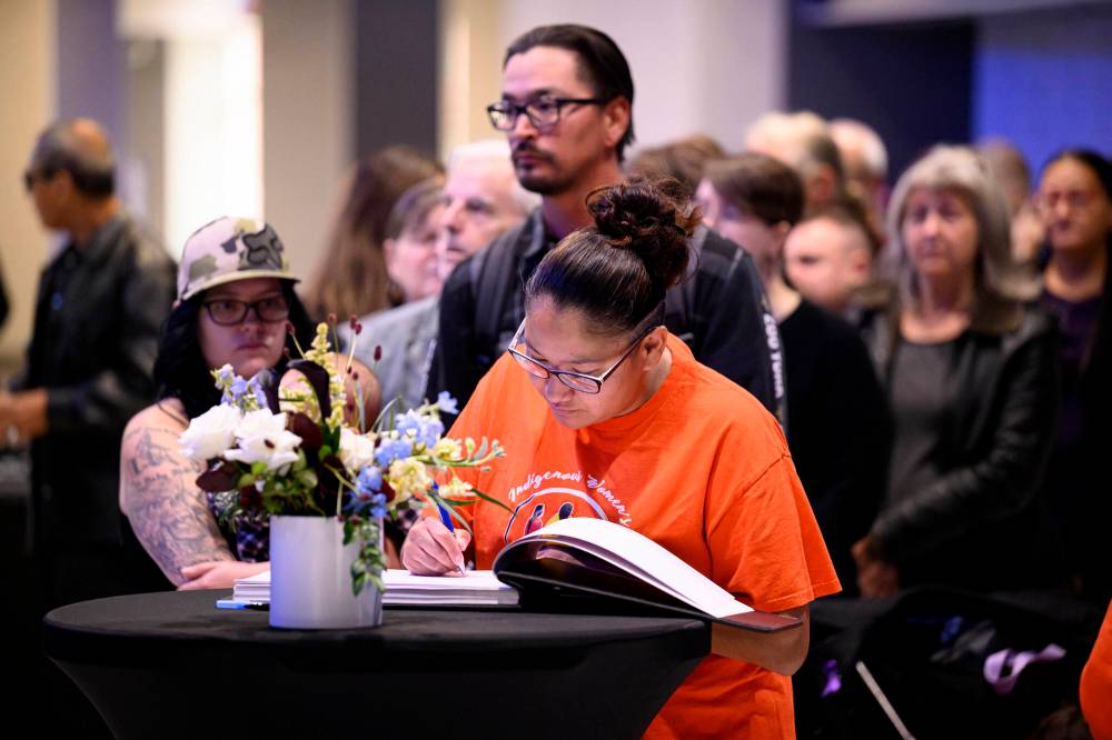 Louise Menow signs a book of condolence. (Mike Sudoma / The Canadian Press)