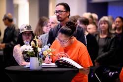 Louise Menow signs a book of condolence. (Mike Sudoma / The Canadian Press)