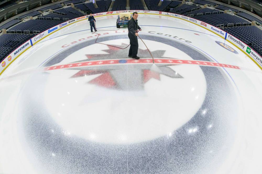 MIKE SUDOMA / FREE PRESS 
                                Engineers Ryan Jones (left) and David Wright paint the Canada Life Centre ice surface white in advance of the Disney on Ice shows. The ice was then covered up to prepare for Bruce Springsteen's concert.