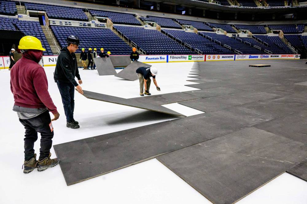 MIKE SUDOMA / FREE PRESS 
                                Crew members prepare the floor at Canada Life centre as they convert the arena from a hockey rink to a music venue early Wednesday morning.