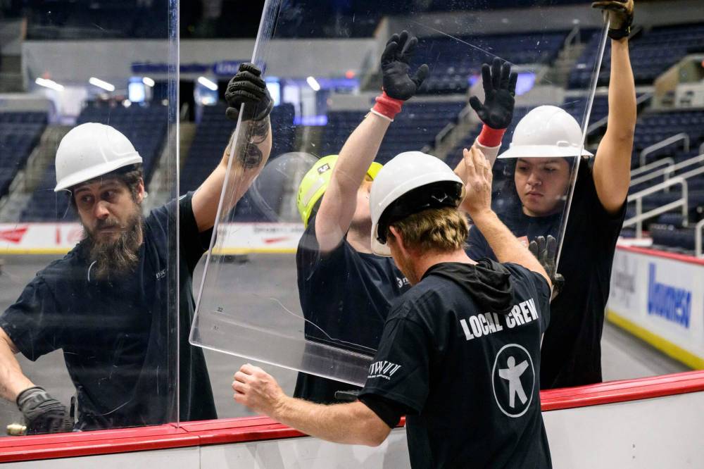 MIKE SUDOMA / FREE PRESS 
                                It’s all hands on deck (and on the glass) as safety is paramount during rink conversion.