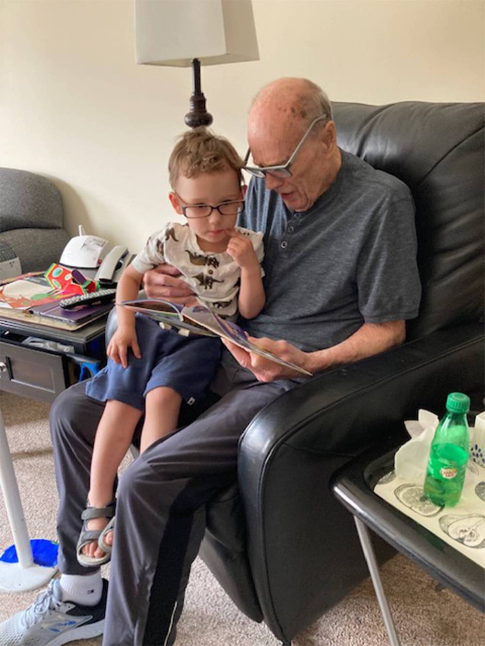 Richard reading to his great-grandson Logan in 2022. Logan didn’t need glasses, he just wanted to be like his great-grandpa. (Supplied)
