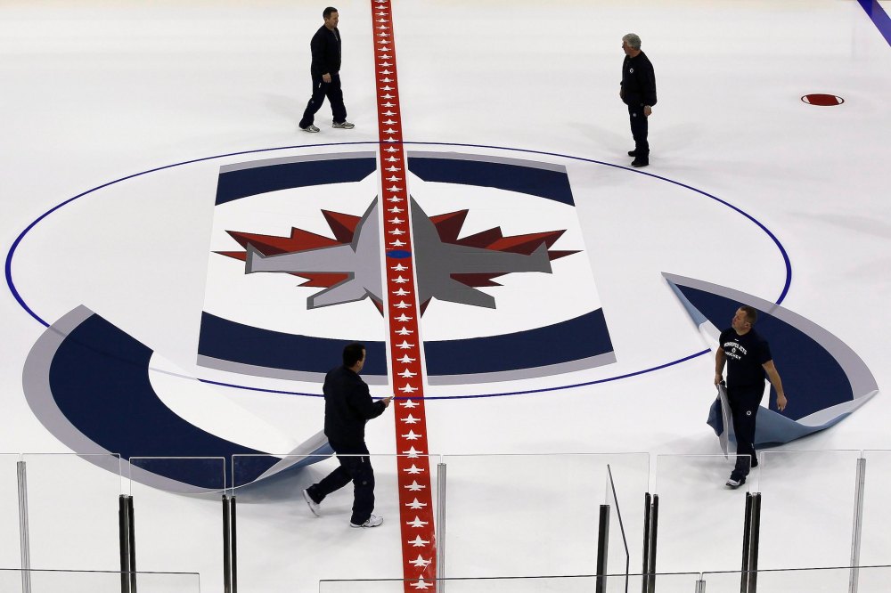 John Woods / THE CANADIAN PRESS FILES
                                Long gone are the days of hand-painted logos, as ice crews install textiles with the Winnipeg Jets logo at centre ice.