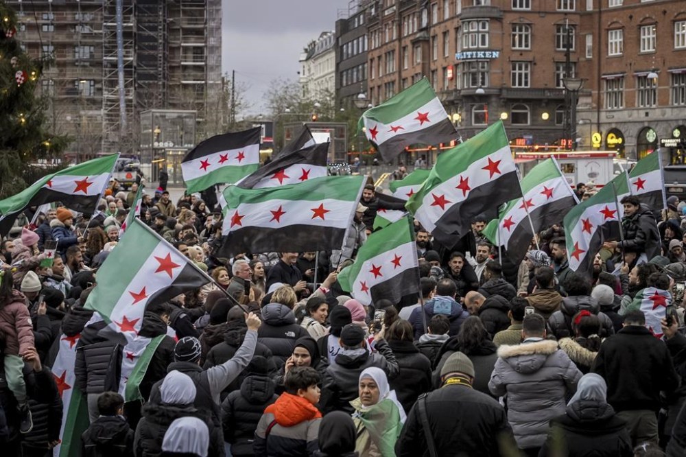 People wave Syrian opposition flags at City Hall Square in Copenhagen, Denmark, Sunday, Dec. 8, 2024. (Emil Nicolai Helms/Ritzau Scanpix via AP)