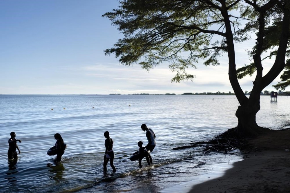 FILE - People wade into the waters of Lake Victoria, the world's second-largest freshwater lake, Nov. 25, 2024, in Entebbe, Uganda. (AP Photo/David Goldman, File)