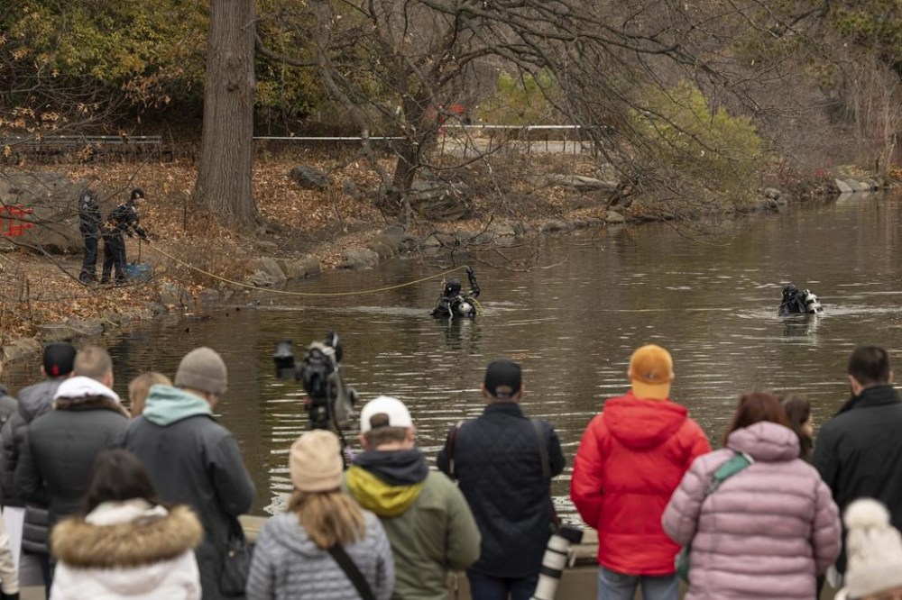 People watch the NYPD officers in diving suits search the lake in the Central Park, Monday, Dec. 9, 2024, in New York. (AP Photo/Yuki Iwamura)