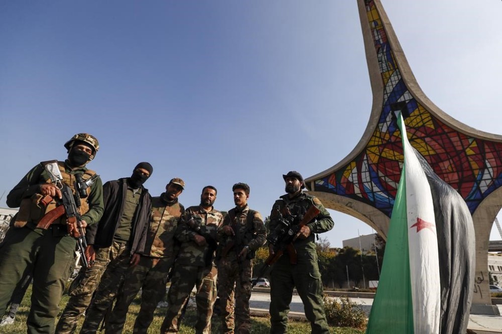 CORRECTS SPELLING Syrian opposition fighters pose for a photograph as they celebrate at Umayyad Square in Aleppo, Syria, Monday, Dec. 9, 2024. (AP Photo/Omar Sanadiki)