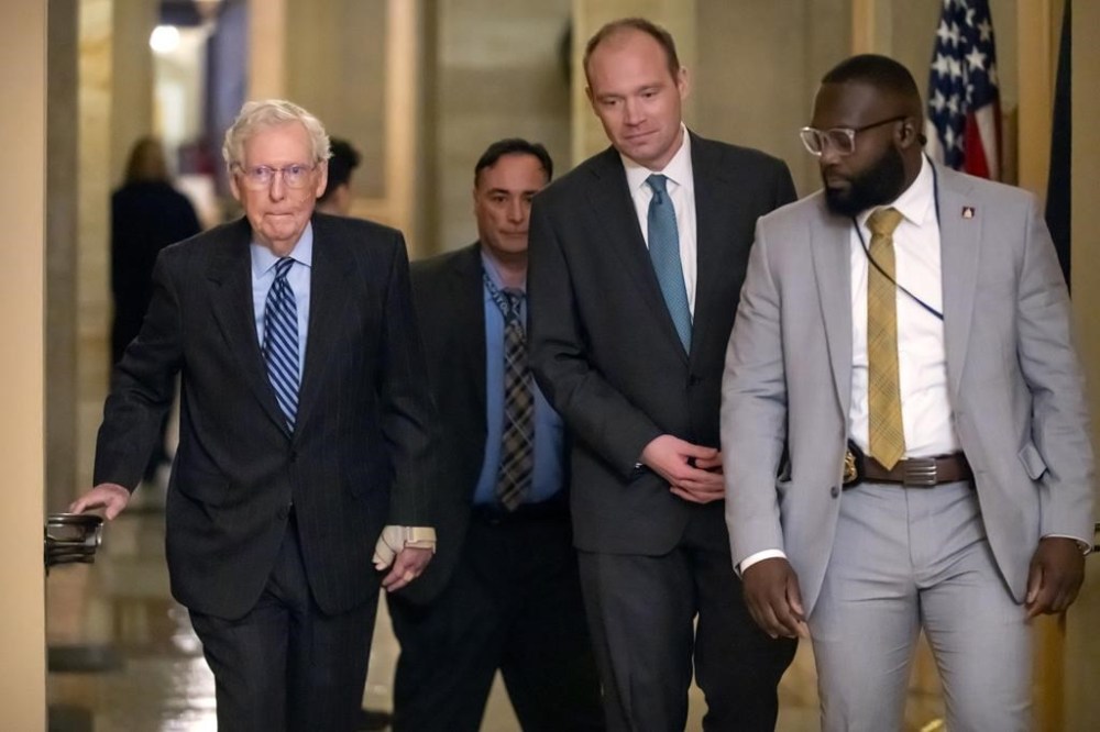 Senate Minority Leader Mitch McConnell of Ky., left, wears a bandage on his face and wrist as he walks to cast a vote on the Senate floor after falling during a luncheon on Capitol Hill, Tuesday, Dec. 10, 2024, in Washington. (AP Photo/Mark Schiefelbein)