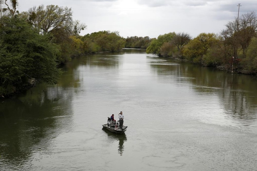 FILE - People fish in the Sacramento-San Joaquin River Delta's Elk Slough near Courtland, Calif., Tuesday, March 24, 2020. (AP Photo/Rich Pedroncelli, File)