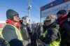 Striking Canada Post employees listen on a speaker to the news that Federal Labour Minister Steven MacKinnon is asking the Canada Industrial Relations Board to send the 50,000 employees back to work, in Toronto on Friday, Dec. 13, 2024. THE CANADIAN PRESS/Frank Gunn