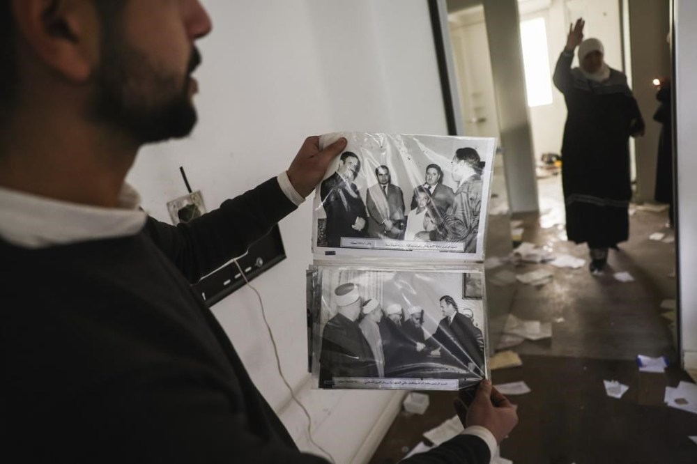 FILE.- A man shows old pictures of the late Syrian President Hafez Assad as civilians ransack the private residence of overthrown President Bashar Assad in the Malkeh district of Damascus, Syria, on Sunday, Dec. 8, 2024. (AP Photo/Ghaith Alsayed,File)