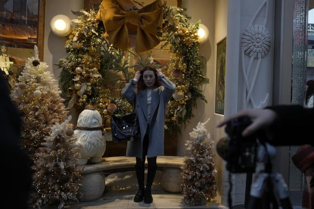 A woman poses for photos near Christmas decorations at a popular mall in Beijing, Sunday, Dec. 15, 2024. (AP Photo/Ng Han Guan)
