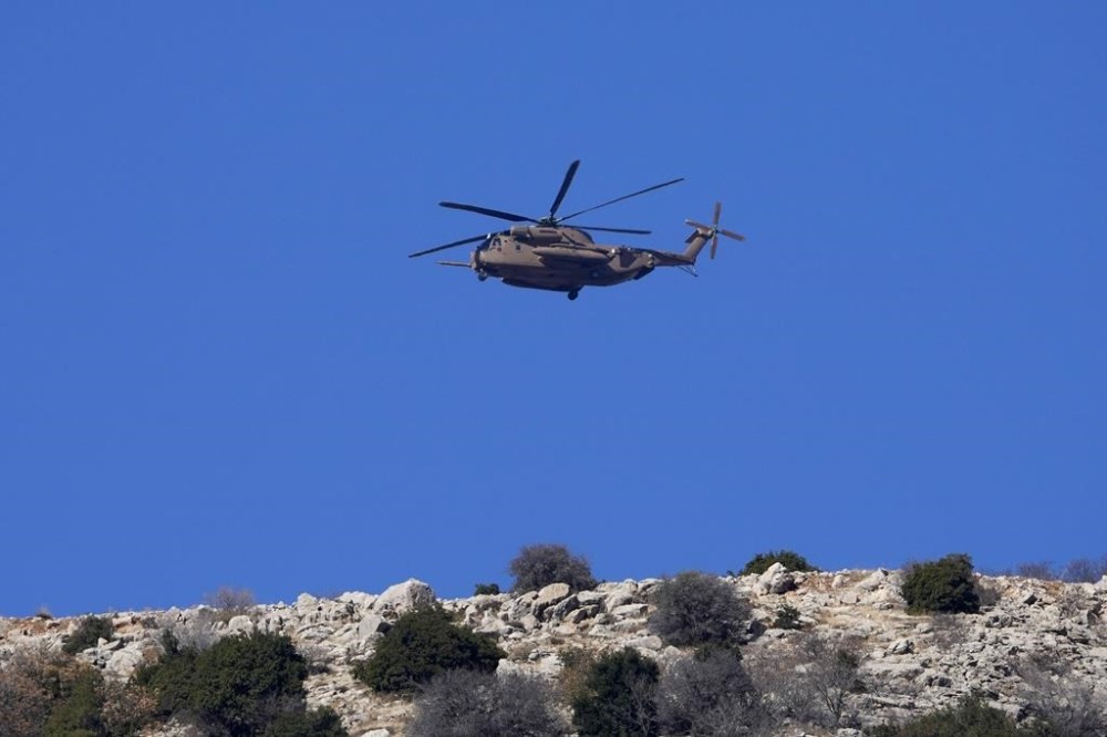 An Israeli Air Force Black Hawk helicopter flies over Mount Hermon near the so-called Alpha Line that separates the Israeli-controlled Golan Heights from Syria, viewed from the town of Majdal Shams, Tuesday, Dec. 17, 2024. (AP Photo/Matias Delacroix)