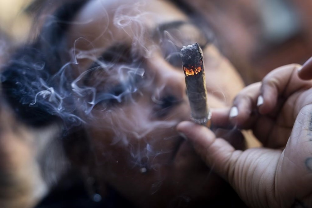 FILE - A person smokes cannabis outside the Smacked