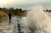 People walk along a sidewalk as waves and debris crash into the breakwater below Dallas Rd. in Victoria, Wednesday, Nov. 20, 2024. THE CANADIAN PRESS/Chad Hipolito